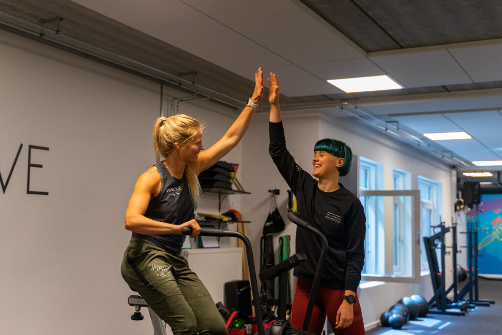 Kvindelig træner hjælper klient med styrketræning i Vanløse