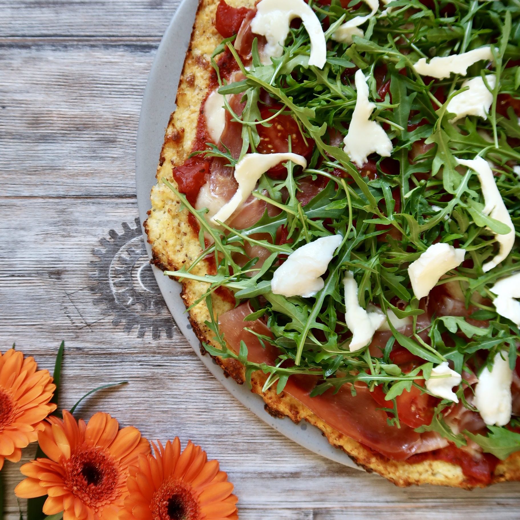 Blomkålspizza med seranoskinke, mozzarella, tomater og rucolasalat